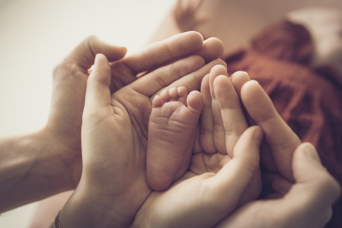 A close view of a parent holding a baby's hand.