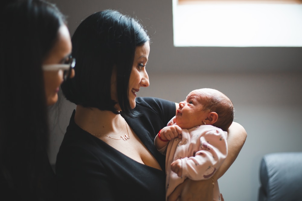 A parent cradling their newborn in soft, warm natural light.