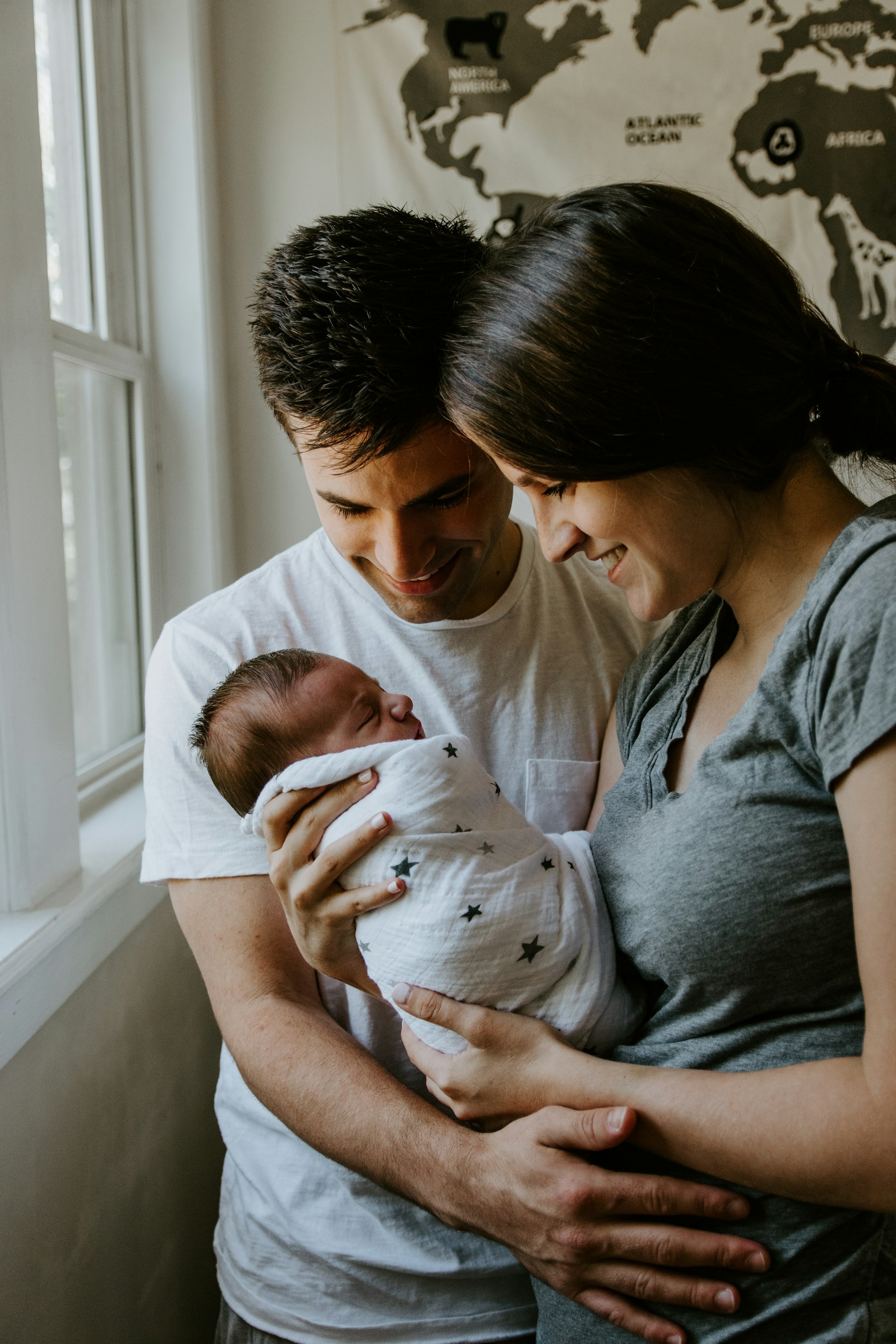 A parent holding a young child at home in warm, natural light.